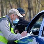 Volunteers Steve Allen and Bruce Winters check in a participant of the Family Holiday Meal distribution program on Nov. 20. Organizers estimate about 900 families received food packages. Below: Vehicles lined up from the Albert Haller Playfields to Washington Street to receive food. Sequim Gazette photos by Matthew Nash