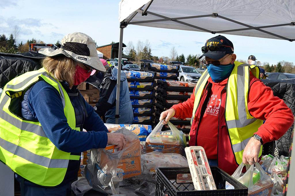 Kathy Strozyk with the Sequim Sunrise Rotary helps Rod Lee, commander of the Carlsborg VFW Post 6787, load up bags for some of the hundreds of families driving through the Family Holiday Meal Bag distribution program. Sequim Gazette photo by Matthew Nash