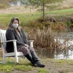 Keith Thorpe/Peninsula Daily News
Nurse and COVID-19 survivor Laura Dotlich sits next to a small pond at her home in rural Port Angeles on Thursday.