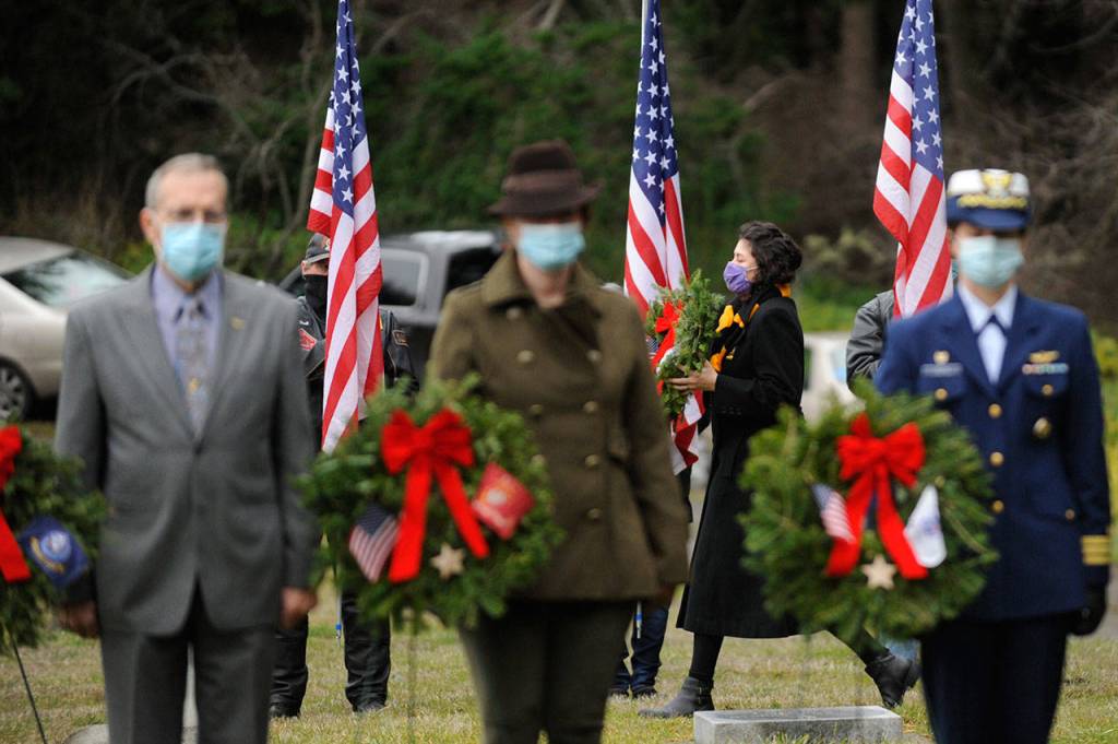 Staff Sgt. Jessica Elizalde-Broders, a U.S. Army veteran, looks to lay a ceremonial wreath at Sequim View Cemetery Saturday. In the foreground are, from left, Cmdr. Bill Benedict (U.S. Navy, ret.), Lance Cpl. Holly Rowan (U.S. Marine Corps veteran) and Cmdr. Joan Snaith (U.S. Coast Guard, Air Station Port Angeles). Sequim Gazette photo by Michael Dashiell