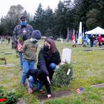 Jennifer Groves of Port Angeles helps sons Blake, 5 (standing), and 2-year-old Bryce, place a wreath on a veterans grave marker Saturday, as Groves stepfather Bobby Yaun looks on. Groves said she attended the event to teach my men to show honor.
