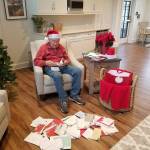 Rodney Hofman opens one of hundreds of Christmas cards sent to him and fellow Dungeness Courte Memory Care residents, following a request from Hofmans family members on social media. Photo courtesy of Dungeness Courte Memory Care
