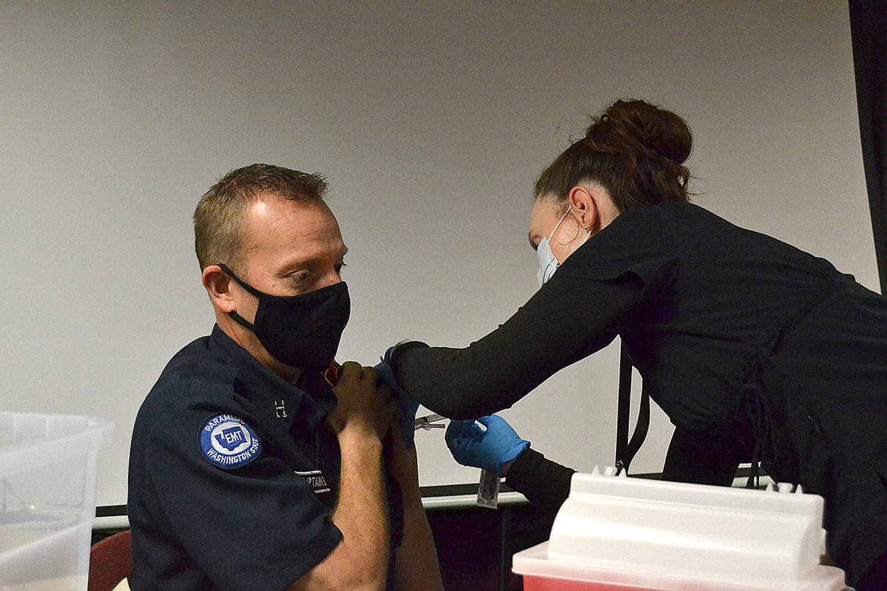 Nurse Kelly Bower with the Jamestown Family Health Clinic gives a Moderna COVID-19 Vaccine to Capt. Derrell Sharp with Clallam County Fire District 3 on Dec. 29 at the fire stations headquarters. Clinic leaders say theyve begun circulating the vaccine to first responders and plan to offer community vaccinations in the coming weeks. Sequim Gazette photo by Matthew Nash