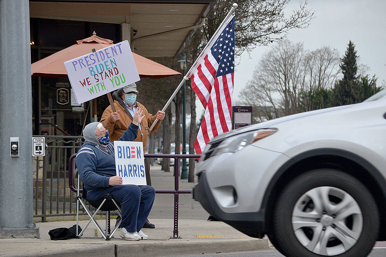 Steve Downer and Brian Grad, both of Sequim, wave to drivers on Jan. 20 as they celebrate the inauguration of President Joe Biden and Vice-President Kamala Harris. Im relieved, Downer said of the inauguration. He hopes their first steps will be to address COVID-19, the economy and environment. Sequim Gazette photo by Matthew Nash