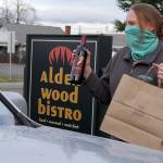 Jessica Schuenemann of Alder Wood Bistro delivers food to a custmer with the restuarant's curbside service. Photo courtesy of Olympic Theatre Arts Center