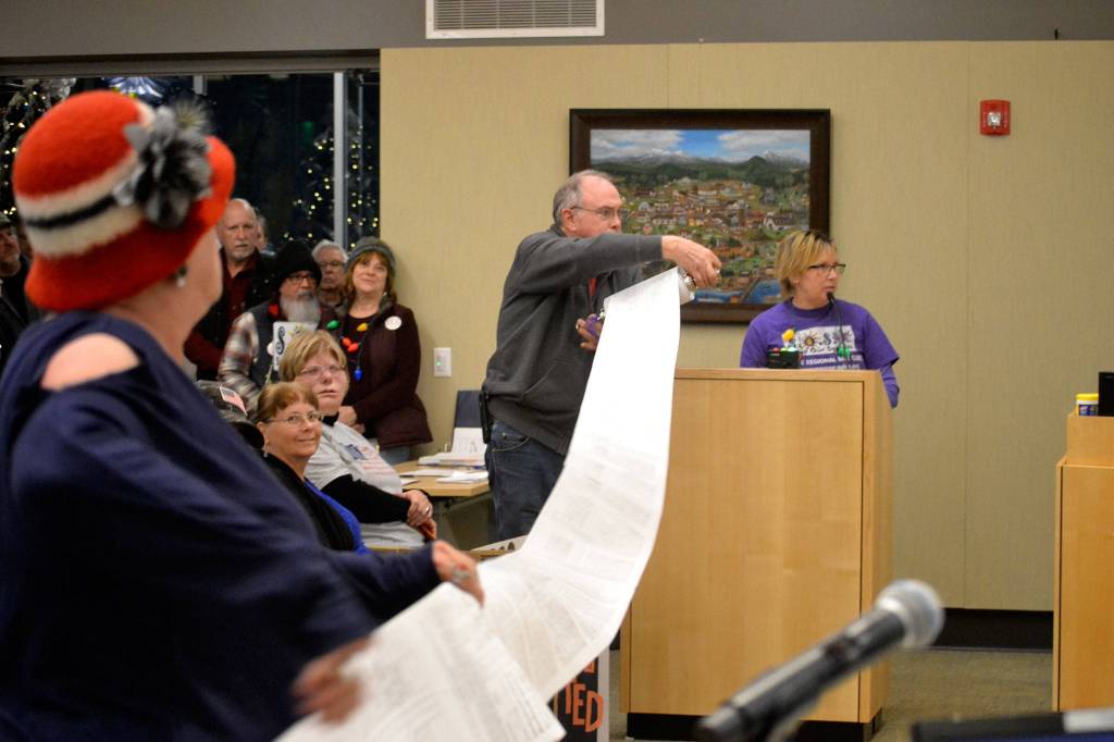 During public comments at the Dec. 9, 2019, Sequim city council meeting, members of Save Our Sequim (SOS), Cheryl Cuccia and George Noa unrolled 2,600 signatures SOS members collected in recent months asking Sequim city councilors to oppose placing the proposed medication-assisted treatment facility in Sequim. Jodi Wilke, on right, said the clinic would add costs for medical, housing, and law enforcement expenses to the public. Sequim Gazette file photo by Matthew Nash