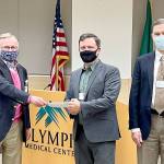 Bruce Skinner, Olympic Medical Center Foundation executive director (at left), presents a check for $55,000 at last weeks OMC Commissioners meeting to commission chair John Nutter, center, and OMC CEO Darryl Wolfe. Submitted photo