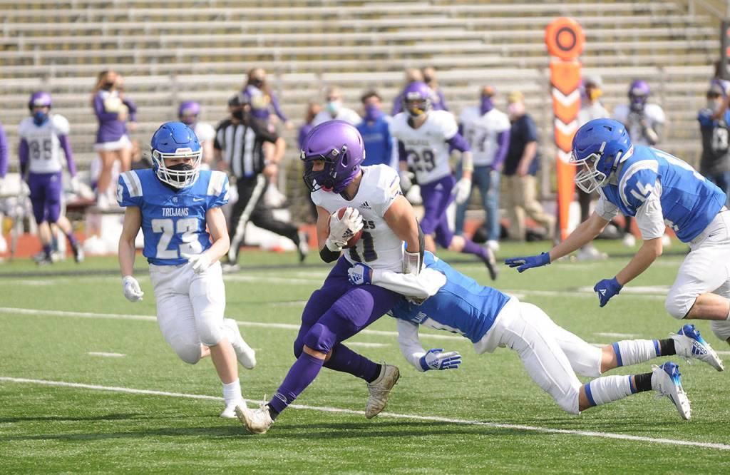 Sequim receiver Michael Young drags defenders for a big gain in the Wolves loss on March 13 at Olympic. Sequim Gazette photo by Michael Dashiell