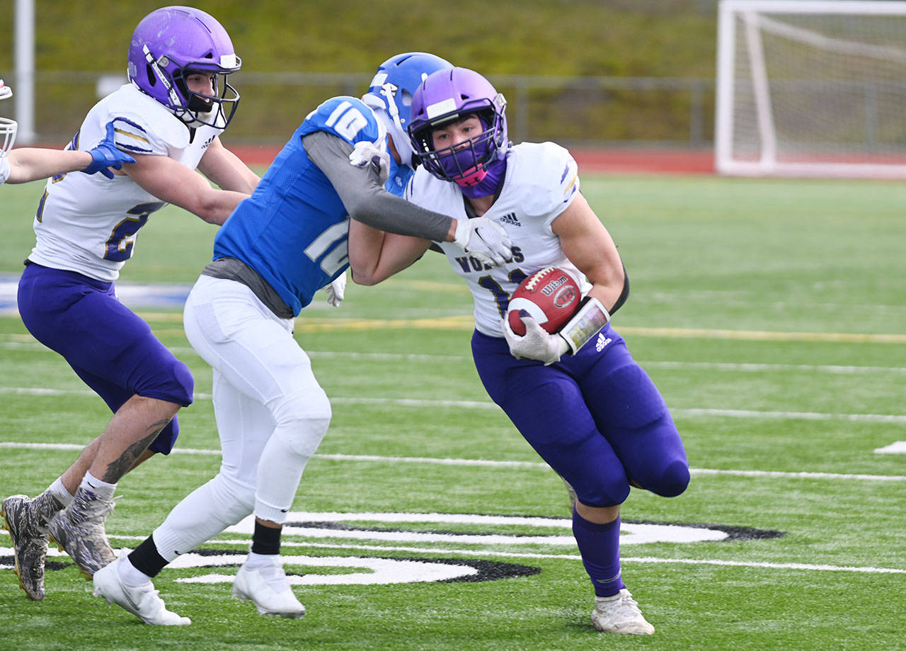 Sequims Michael Young tries to evade the grasp of Olympic safety Xavier Valenzuela in the Wolves 21-12 loss on March 13 at Olympic. Sequim Gazette photo by Michael Dashiell
