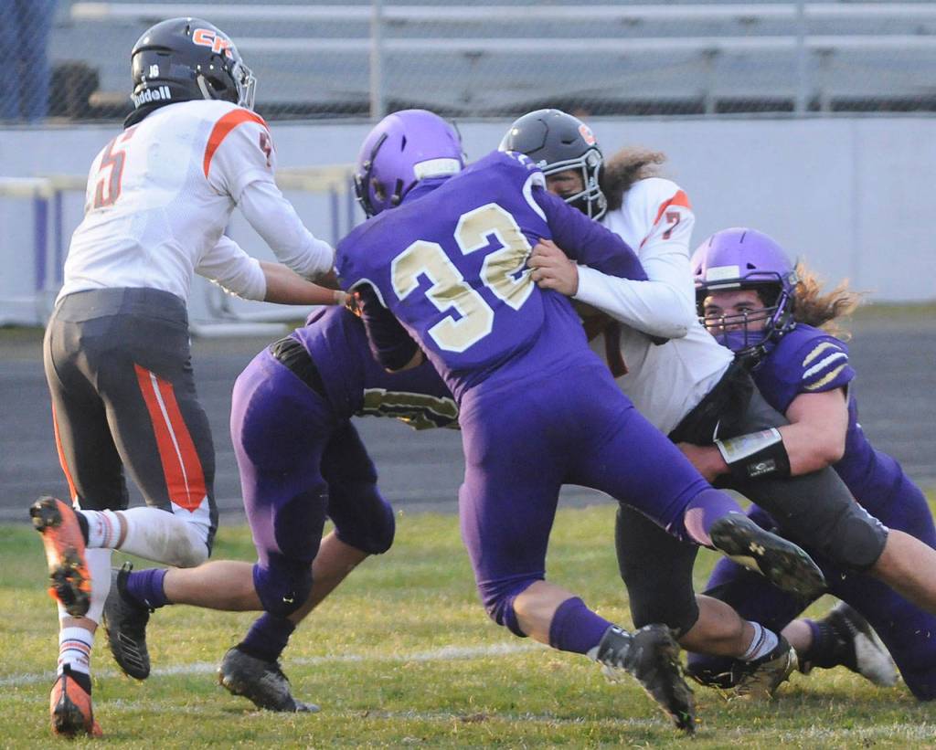 Sequim defenders Truman Nestor (center), Taig Wiker (right) and Garrett Hoesel (background) wrap up Central Kitsap quarterback Kalai Pasai in the first half of Sequims 38-22 win on March 18. Sequim had two key goalline stands against the Cougars. Sequim Gazette photo by Michael Dashiell