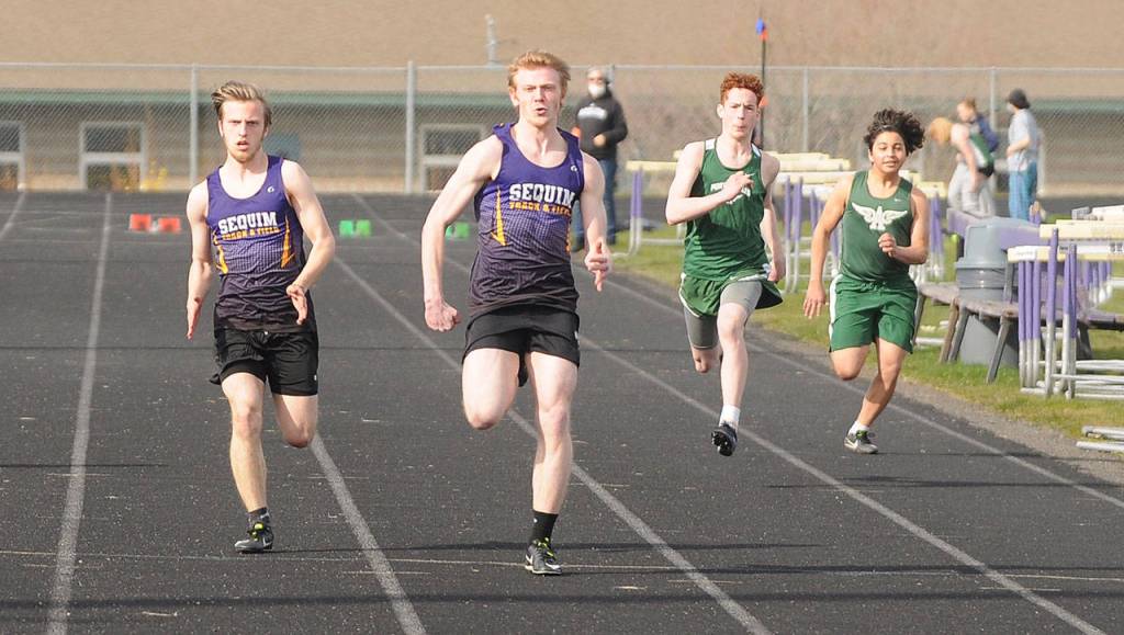 Sequim senior Logan Laxson, second from left, and teammate Theo McMurray race to a 1-2 finish in the 100-meter dash on March 31 in Sequim. Laxson finished in 11.69 seconds, McMurray in 12.00 seconds. Sequims Zack Gufler, not pictured was third (12.93). Laxson took three first places at last weeks meet, taking the 100, 200 and long jump. Sequim Gazette photo by Michael Dashiell