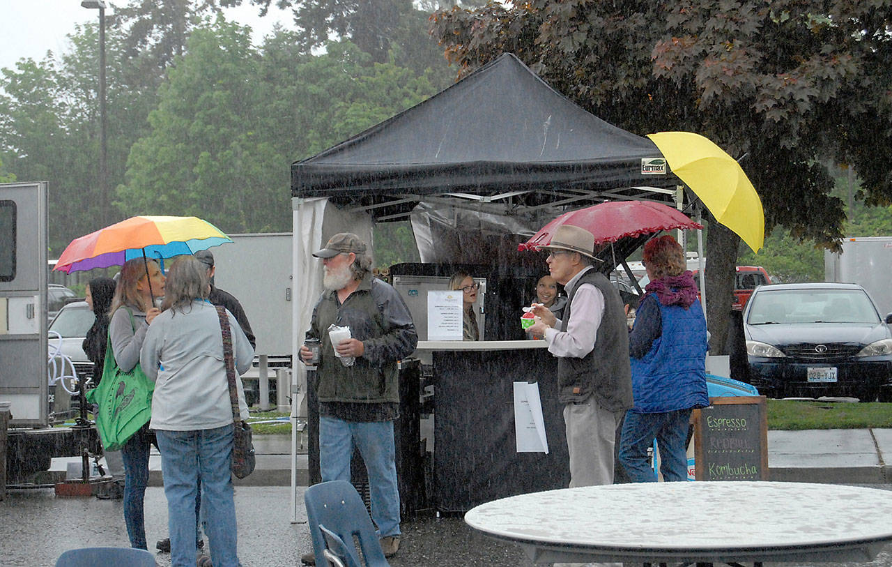 News Festival patrons stand in a pouring rain at a food booth during the 2019 Juan de Fuca Festival of the arts. Photo by Keith Thorpe/Olympic Peninsula News Group