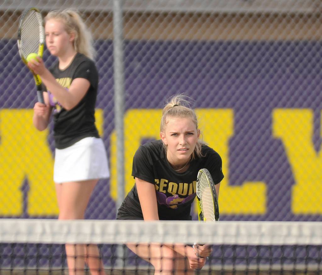 Kendall Hastings, foreground, awaits as sister McKenna prepares to serve in an Olympic League match in late March. The siblings went 14-0 on the 2021 season. Sequim Gazette photo by Michael Dashiell