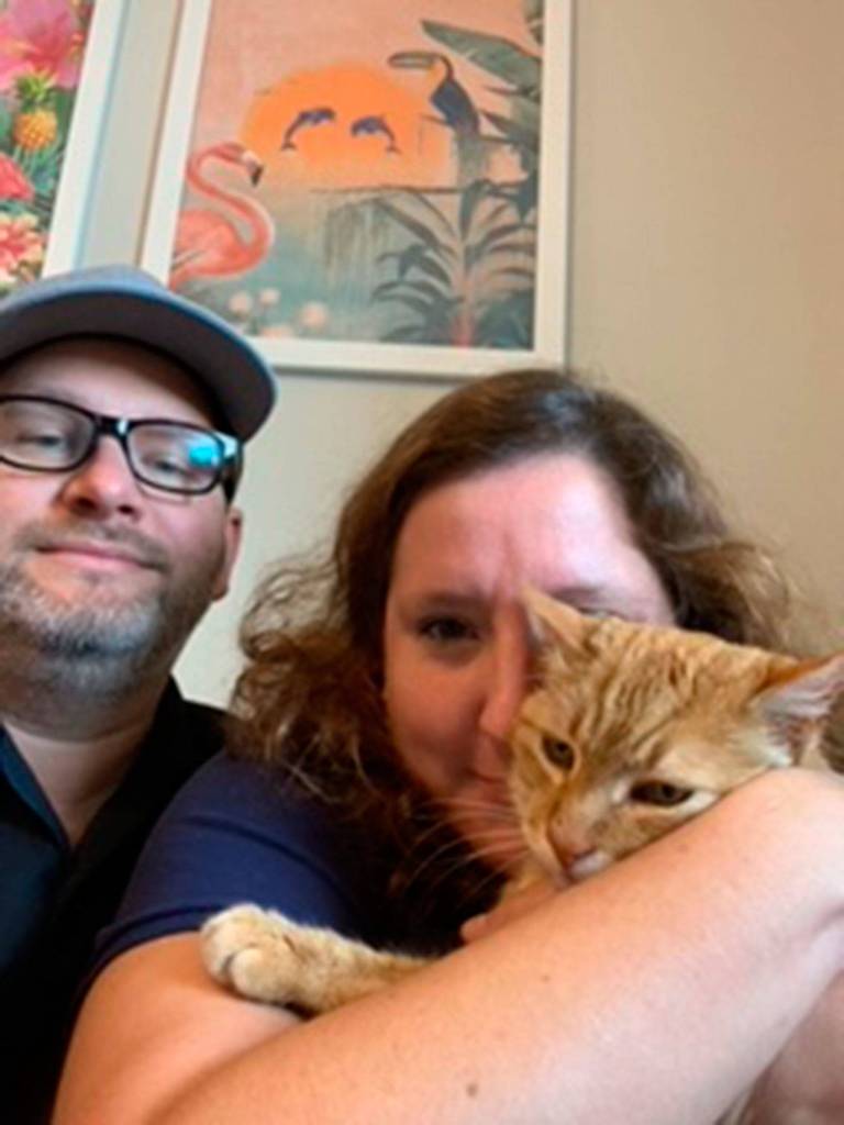 Steven and Christine Taggart take a family photo with Pumpkin the cat. The couple looked for the cat for eight months after he went missing during their brief stay in Sequim. Christine stay connected online in pet finder groups and paid for signs, which helped find Pumpkin. Photo courtesy of Christine Taggart
