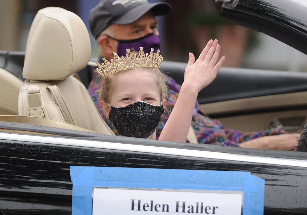 Eleanor Jones, who along with Emma Chapman represents Helen Haller Elementary School on the 2021 Sequim Irrigation Festival Junior Royalty court, waves to the crowd in downtown Sequim; her chauffeur is Jim Stoffer. Sequim Gazette photo by Michael Dashiell