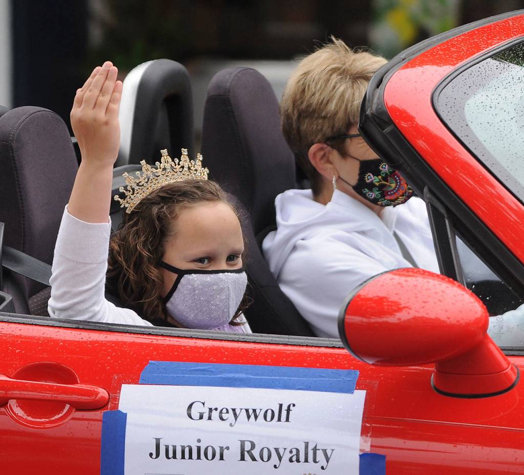 Evie Judd, who along with Aleah Daniels represents Greywolf Elementary School on the 2021 Sequim Irrigation Festival Junior Royalty court, waves to the crowd in downtown Sequim; her chauffeur is Monica Dixon. Sequim Gazette photo by Michael Dashiell