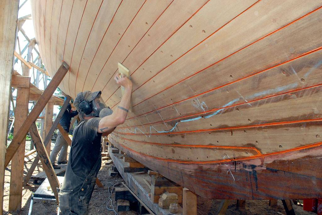 Last week, Shipwright Pete Steion of Port Townsend sands the bottom of the cutter Tally Ho in early May. Photo by Keith Thorpe/Olympic Peninsula News Group