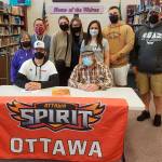 Michael Young, seated next to his grandfather Paul Arnbrister, announces last week his intent to play football at Ottawa University in Surprise, Ariz. Sequim High teammate Walker Ward also signed an intent to plat at Ottawa this fall. Pictured with Young are, back row from left, Kim Thompson, Denny Thompson, Kikayla Halady, Zoey Thompson, Diana Young, Johnnie Young and Chris Young. Submitted photo