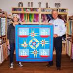 Quilt maker Dory Miller of Crazy Horse Quilting and Sequim Bay Yacht Club commodore Jerry Fine display a quilt up for raffle at A Stitch in Time Quilt Shoppe in Sequim. Proceeds go to Volunteer Hospice of Clallam County for respite care. Submitted photo