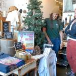 Hayley Sharpe, owner of MOSS boutique, left, talks with Kayla Oakes, executive director of the Juan de Fuca Festival of the Arts, on Tuesday next to a display of festival merchandise offered at the downtown Port Angeles shop. The festival's concerts and street fair return to the Vern Burton Community Center this Friday through Sunday. (Keith Thorpe/Peninsula Daily News)