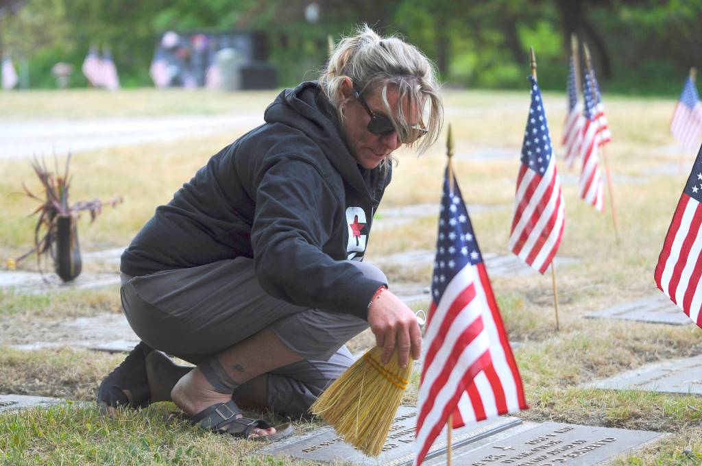 Above: Kimi Tinsley of Sequim clears grave markers of grass and debris following a Memorial Day event lead by local American Legion posts at Sequim View Cemetery on May 31. Tinsleys father and grandfather were both war veterans.