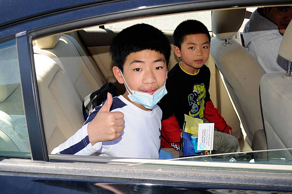 Can Bin Li gives a thumbs up with brother Can Hui Li behind him after participating in a drive-through graduation ceremony on June 17 for fifth-graders going to middle school.