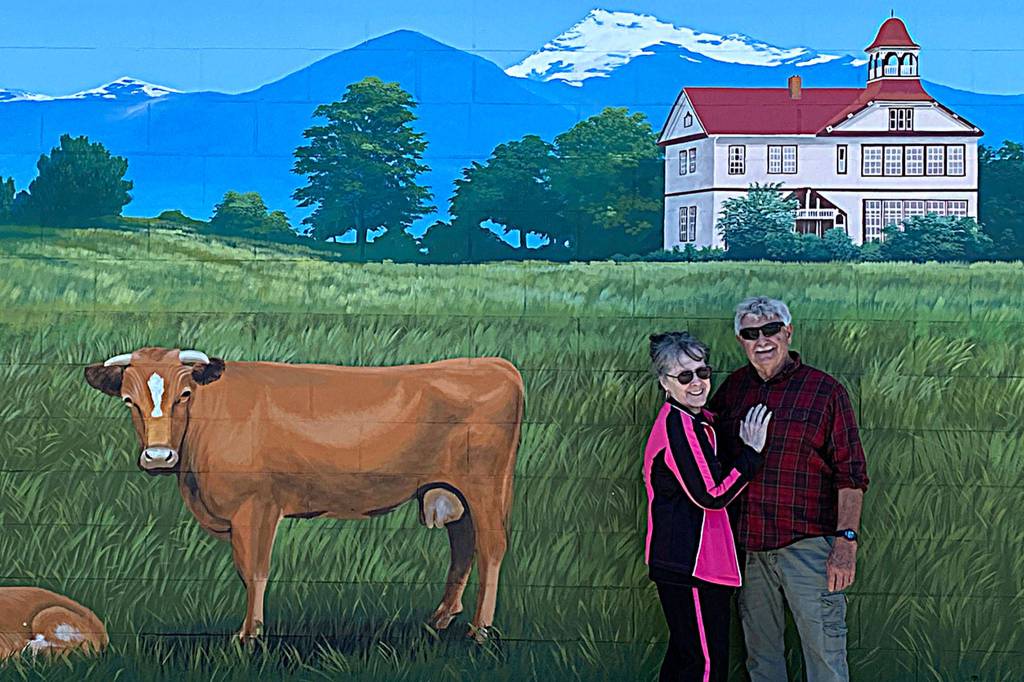 Judy and Bob Stipe stand underneath Andy Eccleshalls depiction of the Dungeness Schoolhouse. Judy Stipe said Eccleshall is a renaissance man and such a delight to work with. (The mural) is a beautiful thing for all of us who have seen this place grow, she said. Photo courtesy Katherine Vollenweider