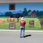 Bob Fermanis of Port Angeles admires the new mural at A Stitch in Time Quilt Shoppe last week as artist Andy Eccleshall works to finish a depiction of a 1937 AUTOCAR.
