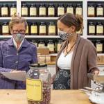 Dandelion Botanical Company owner Kachi Cassinelli, left, consults with manager Britney Bakken. Behind them large amber glasses line one wall of the old Nashs Farm Store. Sequim Gazette photo by Emily Matthiessen
