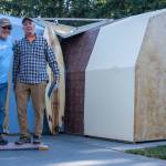 Brad Griffith and Gary Young demonstrate the strength of their modular shelter panels outside the demo version in Sequim. Behind Young is one of his fiberglass-free surfboards. Sequim Gazette photo by Emily Matthiessen