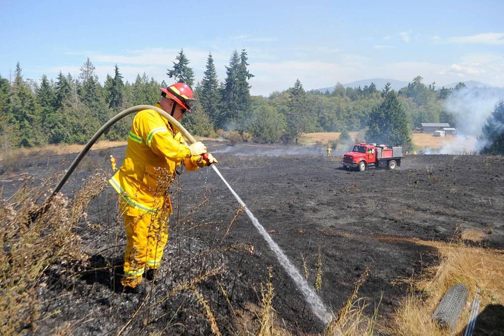 Firefighters with Clallam County Fire District 3 and District 2 and several other agencies contained the July 27 brush fire in less than two hours. Firefighters with the Department of Natural Resources were called in to investigate the fires cause and further contain the fire on Tuesday night. Sequim Gazette photo by Matthew Nash