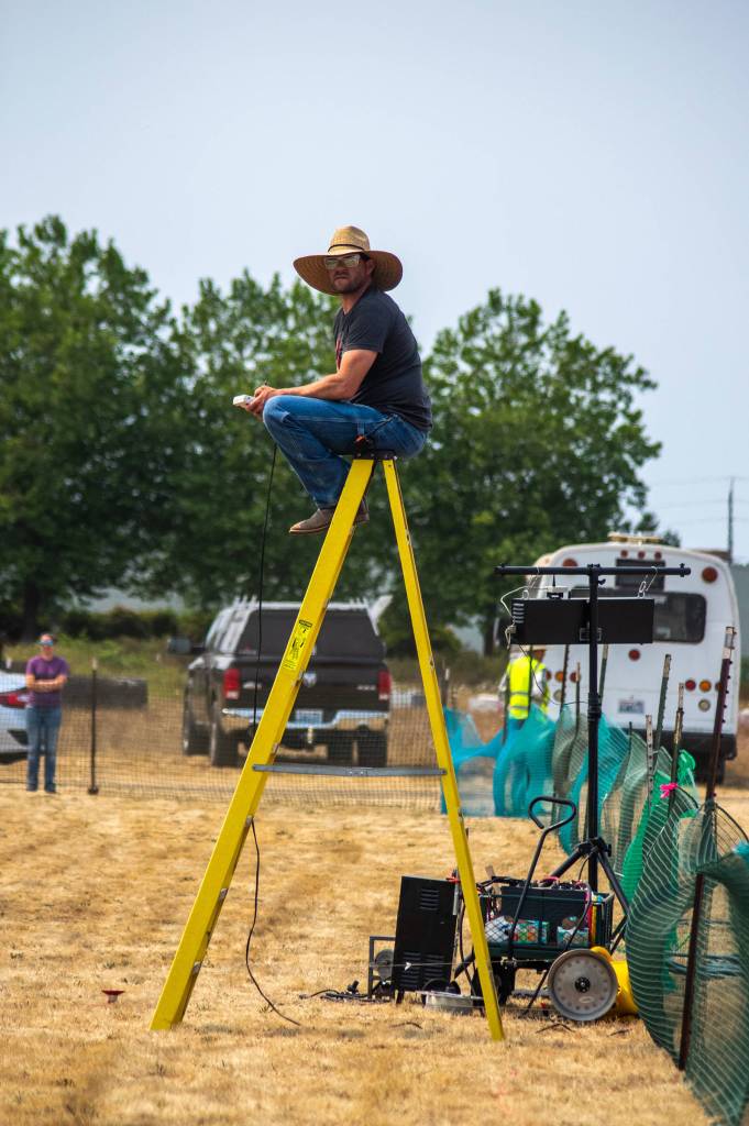 Andy Hilzer of Ellensburg sits atop a yellow ladder as he controls the speed and timing of the white plastic which zips along a line to encourage dogs to run at their fastest speed. He says that he gauges the distance between the plastic and the dog to keep it close enough that they dont loose interest but far enough that they cant catch it during the fast CAT speed challenge. Sequim Gazette photo by Emily Matthiessen