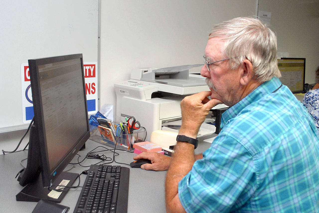 Clallam County election worker Daniel Cain of Sequim consults a database of signatures to verify ballots on Aug. 3 at the courthouse in Port Angeles. Photo by Keith Thorpe/Olympic Peninsula News Group