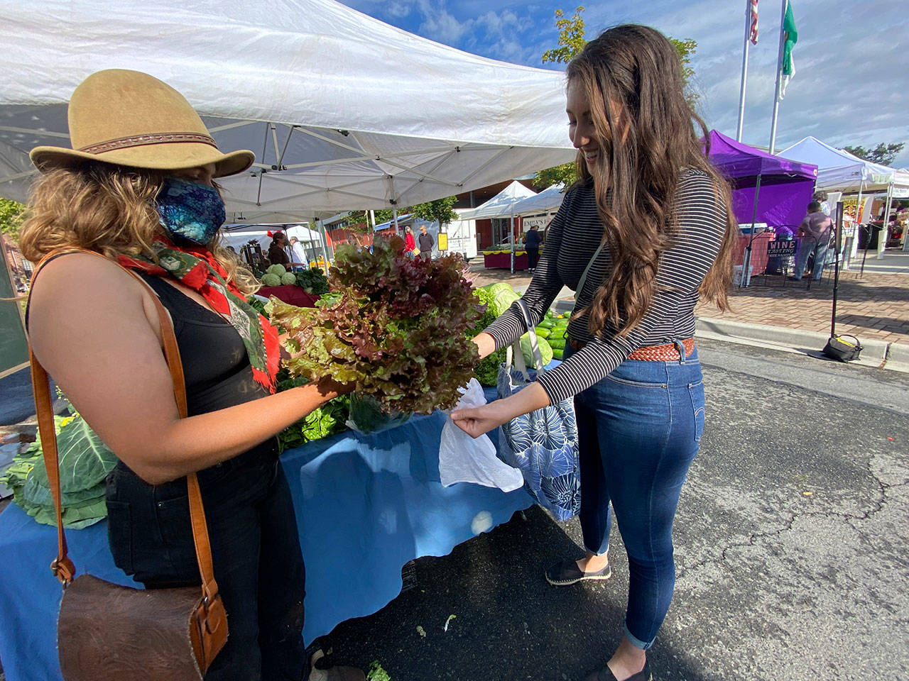 Parker of River Run Farm helps a market guest pack up a head of fresh lettuce. Photo by Emma Jane EJ Garcia