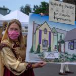 Carol Willis, former Executive Director of Olympic Theatre Arts, holds up an illustration of the future redesign of the the theaters exterior at OTAs Renaissance fundraiser on Aug. 22. Sequim Gazette photo by Emily Matthiessen