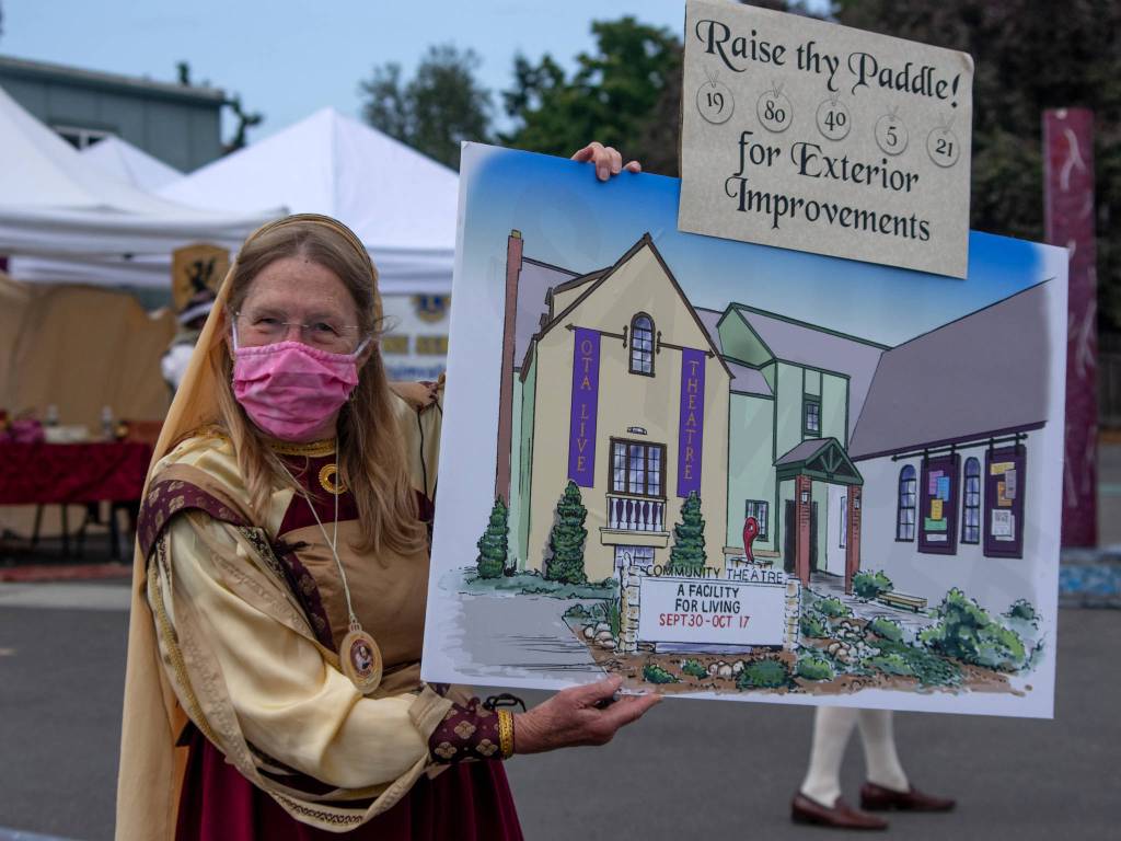 Carol Willis, former Executive Director of Olympic Theatre Arts, holds up an illustration of the future redesign of the the theaters exterior at OTAs Renaissance fundraiser on Aug. 22. Sequim Gazette photo by Emily Matthiessen