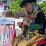 Suzanne Horn plays her mandolin in a colorful booth outside Olympic Theatre Arts in Sequim, during their fundraiser on Aug. 22. "It's a fun instrument," she said. "Nice and small with kind of a bell sound."  Sequim Gazette photo by Emily Matthiessen
