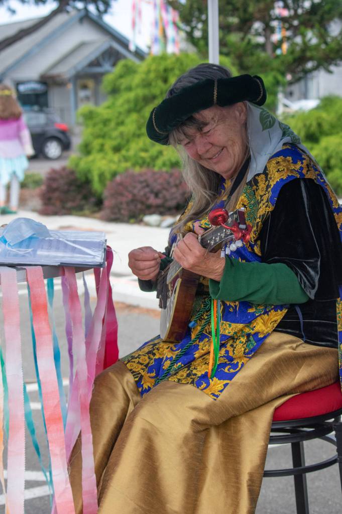 Suzanne Horn plays her mandolin in a colorful booth outside Olympic Theatre Arts in Sequim, during their fundraiser on Aug. 22. "It's a fun instrument," she said. "Nice and small with kind of a bell sound."  Sequim Gazette photo by Emily Matthiessen