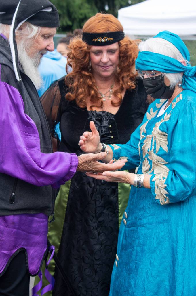 Jim the Traveler Bufen and Shelly Ament listen as Eve Datisman reads Bufens palm at Olympic Theatre Arts Renaissance Faire in Sequim on Aug. 22. Sequim Gazette photo by Emily Matthiessen