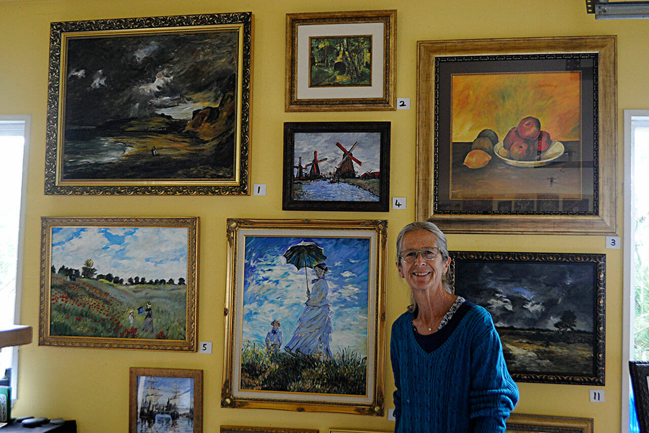 Carrie Rodlend plans to auction off more than 30 reimagined classic paintings, such as Claude Monets Woman with a Parasol – Madame Monet and Her Son on Saturday, Sept. 11 from her home studio at 562 Holgerson Road in Dungeness. Shes worked more than a year beside her students on reimagining classic paintings to teach new techniques. Sequim Gazette photo by Matthew Nash