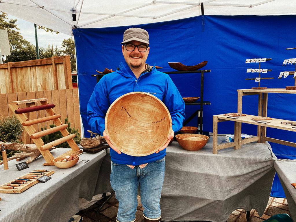 Davis Stevenson shows off a wooden bowl at the Northwest Beach Works booth at the Sequim Farmers & Artisans Market. Photo by Emma Jane EJ Garcia