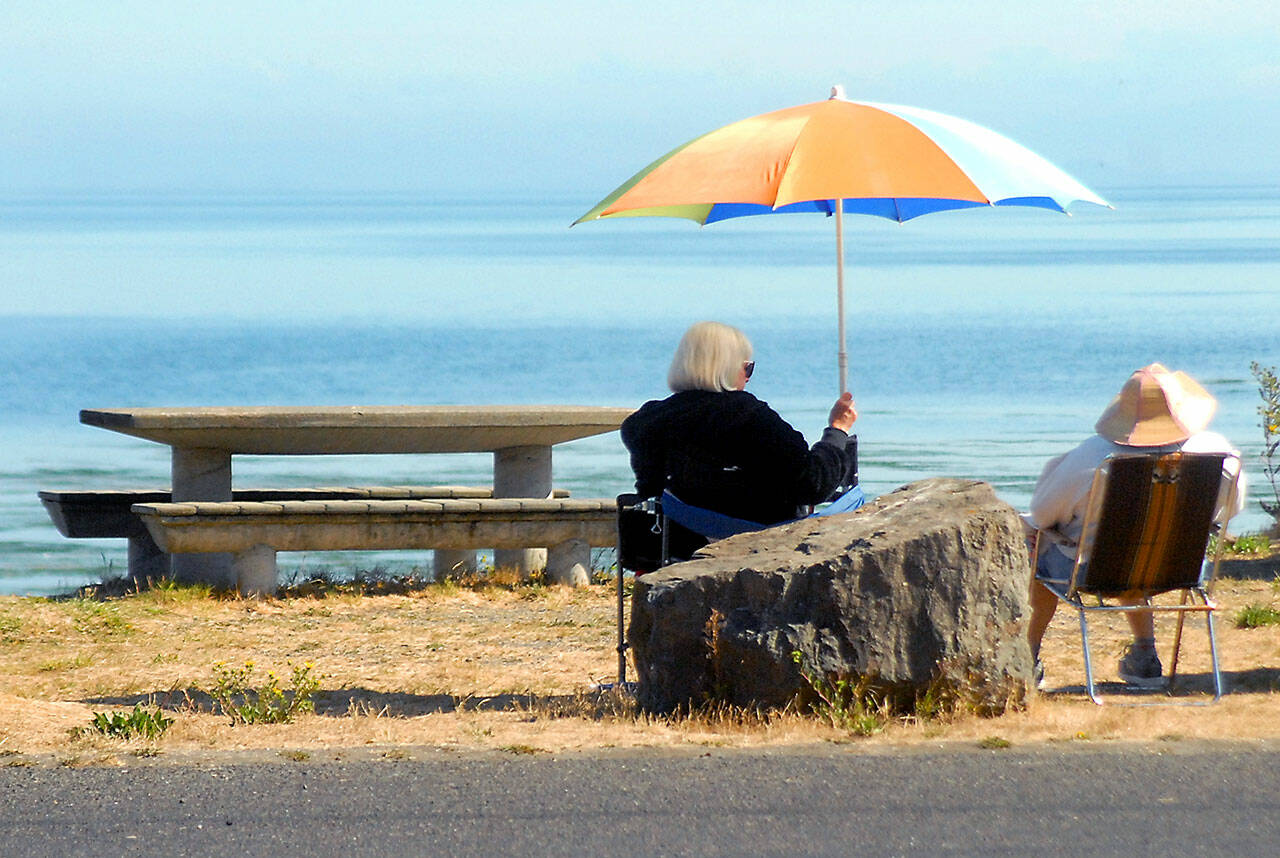 Kathleen Krecklow sits under an umbrella as she talks with Jo Ehly on the shore of Dungeness Bay at Dungeness Landing County Park on Sept. 1. The women, both of Sequim, were sharing the morning with other friends in a weekly gathering. Photo by Keith Thorpe/Olympic Peninsula News Group