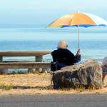 Kathleen Krecklow sits under an umbrella as she talks with Jo Ehly on the shore of Dungeness Bay at Dungeness Landing County Park on Sept. 1. The women, both of Sequim, were sharing the morning with other friends in a weekly gathering. Photo by Keith Thorpe/Olympic Peninsula News Group