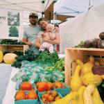 Rich Austin and Lindsey Soha, holding Rhea, offer a variety of edibles at the Rhea Sunshine Farm booth at the Sequim Farmers & Artisans Market. Photo by Emma Jane EJ Garcia