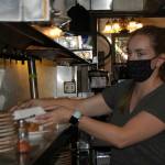 Christine VanDeen, server at the Oak Table Café, takes some plates for customers sitting in an outside patio area. The restaurant is one of many Sequim eateries to offer both outside and inside seating for customers with/without COVID-19 vaccination cards. Sequim Gazette photo by Matthew Nash