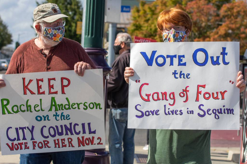 Bill May and Kevin May hold up hand-lettered signs at a rally in Sequim on Sept. 18. Kevin May says, I think its important to get city council members that are elected by the people, not appointed by the council…. We have these really partisan city council members who were kind of forcing things on the city and dividing. Sequim Gazette photo by Emily Matthiessen