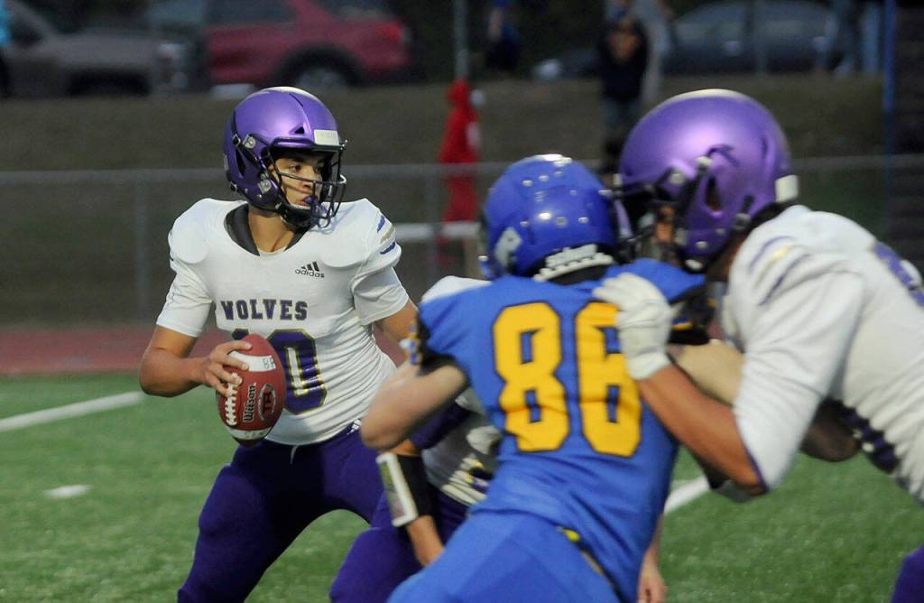 Sequims Lars Wiker, left, looks to avoid Bremertons pass rush in the first half of the Wolves 35-29 loss to the Knights on Sept. 30. Sequim Gazette photo by Michael Dashiell