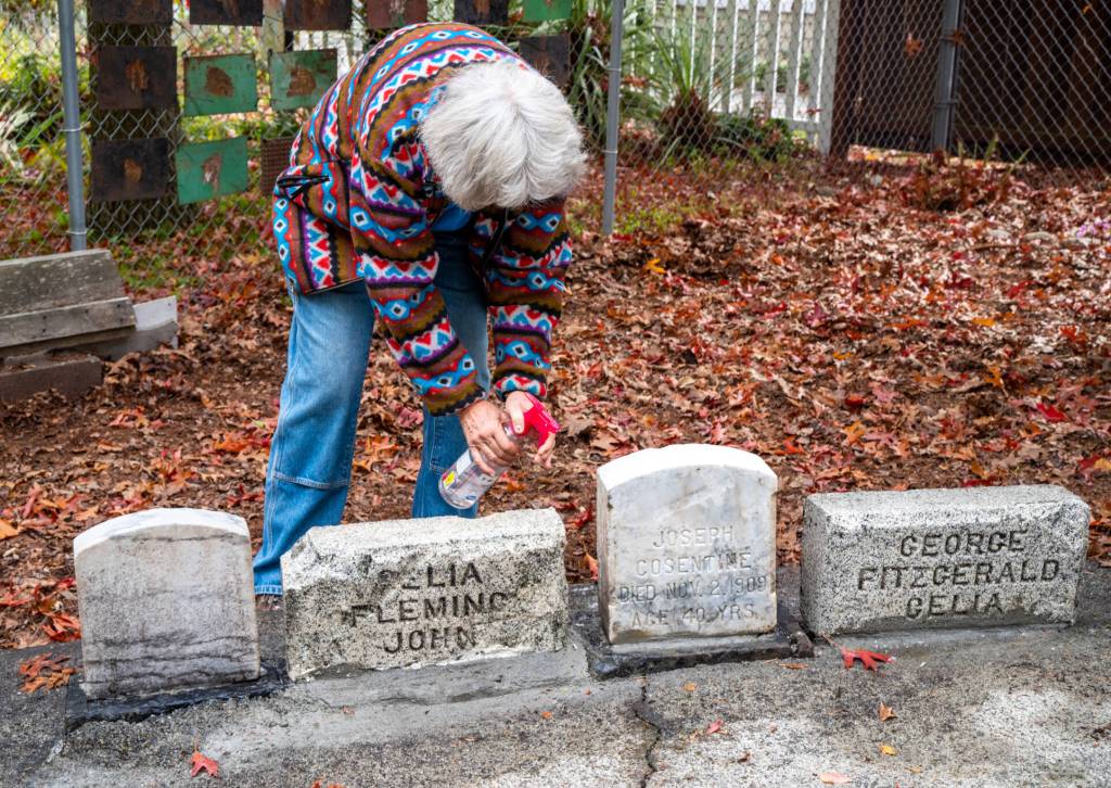 Marianne Burton of the Michael Trebert Chapter of the Daughters of the American Revolution, sprays a solution called D/2 (TM) on the headstone of Joseph Cosentine as part of an effort to restore and preserve the headstones of Pioneer Memorial Park in Sequim, which used to be a cemetery before flooding from Bell Creek caused it to close in 1919. Most of the graves and headstones were removed but some headstones remain in a corner of the park. Sequim Gazette photo by Emily Matthiessen