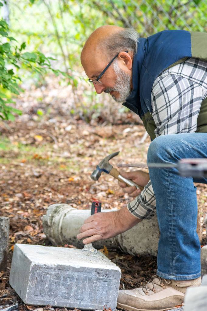 Chris Smith scrapes away old white mortar off the headstone of Oscar Larson, a Swedish native who arrived in New York in 1881. Larsons sister lived in New Dungeness, and he worked at the lumber mill in Port Discovery. Larson had his citizenship signed at the Superior Court of New Dungeness in 1895 with two signed character witnesses. Larsons headstone was attached to an unmatching base in the 1960s, when the Sequim Prairie Garden Club made a memorial corner for the headstones that were left in Pioneer Memorial Park after the majority of the cemetery was relocated in the early 1900s. Sequim Gazette photo by Emily Matthiessen