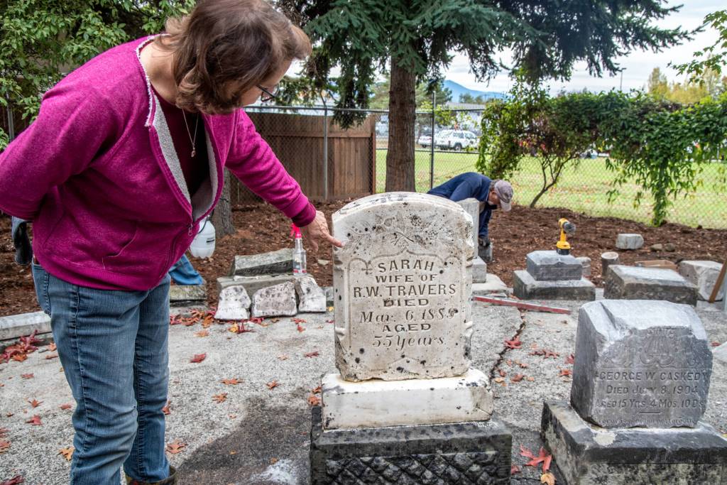 Suzan Mannisto points to the floral decoration on the headstone of Sarah Travers  the Sequim Prairie Garden Club may paint it next spring. According to Patricia Hudson, historian, Sarah was born in 1835 of French Indian parentage, and married Captain Robert Warren Travers in 1868 in Sequim. The couple had one son, George Warren Travers. Their only daughter, Margaret Jane, was born in 1870 at Port Williams, married Albert Edward Simmons on July 2nd, 1889 in New Dungeness, WA and died there on July 4th, 1953; they had 2 sons and 1 daughter. Sequim Gazette photo by Emily Matthiessen